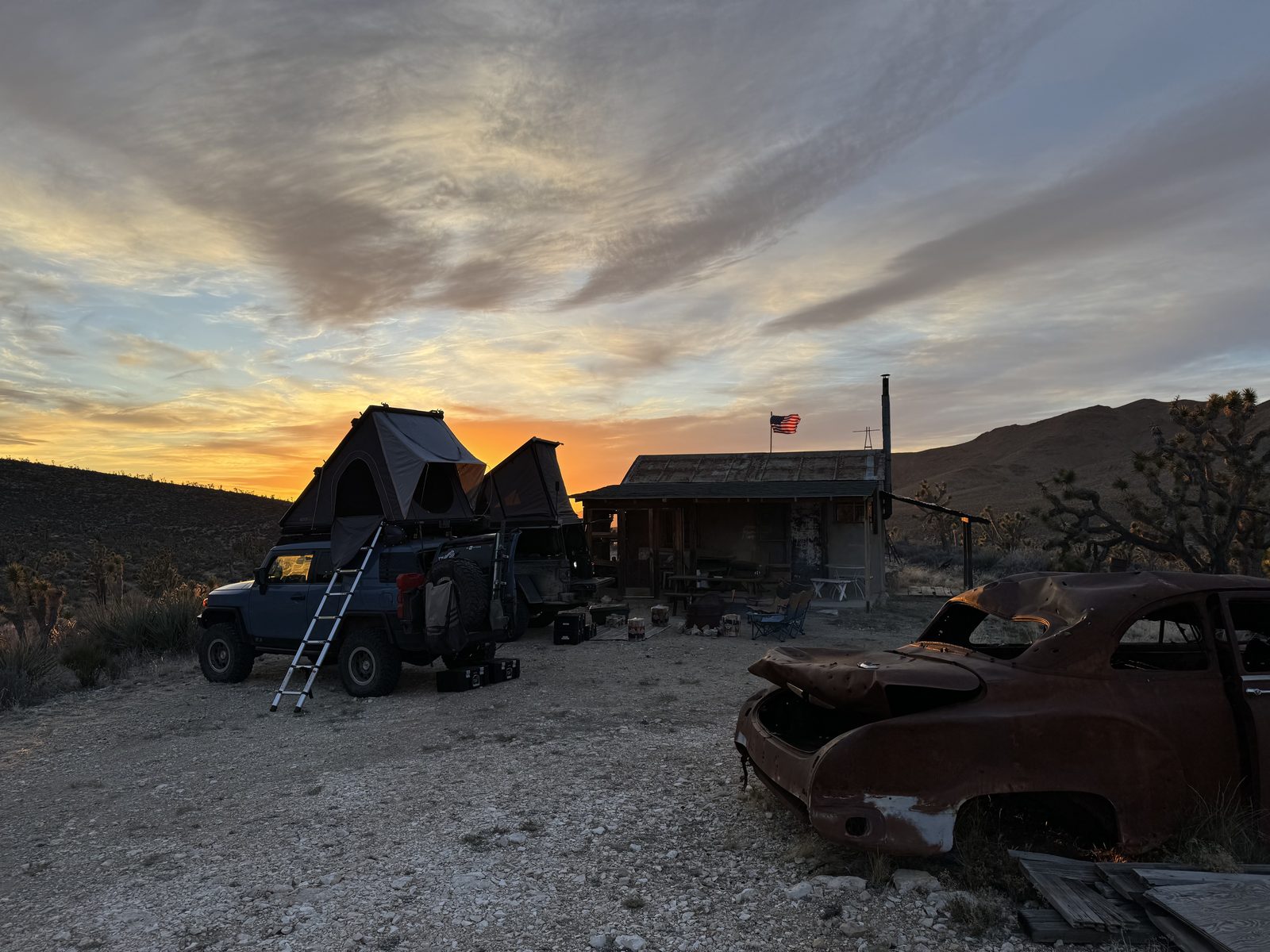 Tents up beside Rodger's Cabin at sunset, flag flying